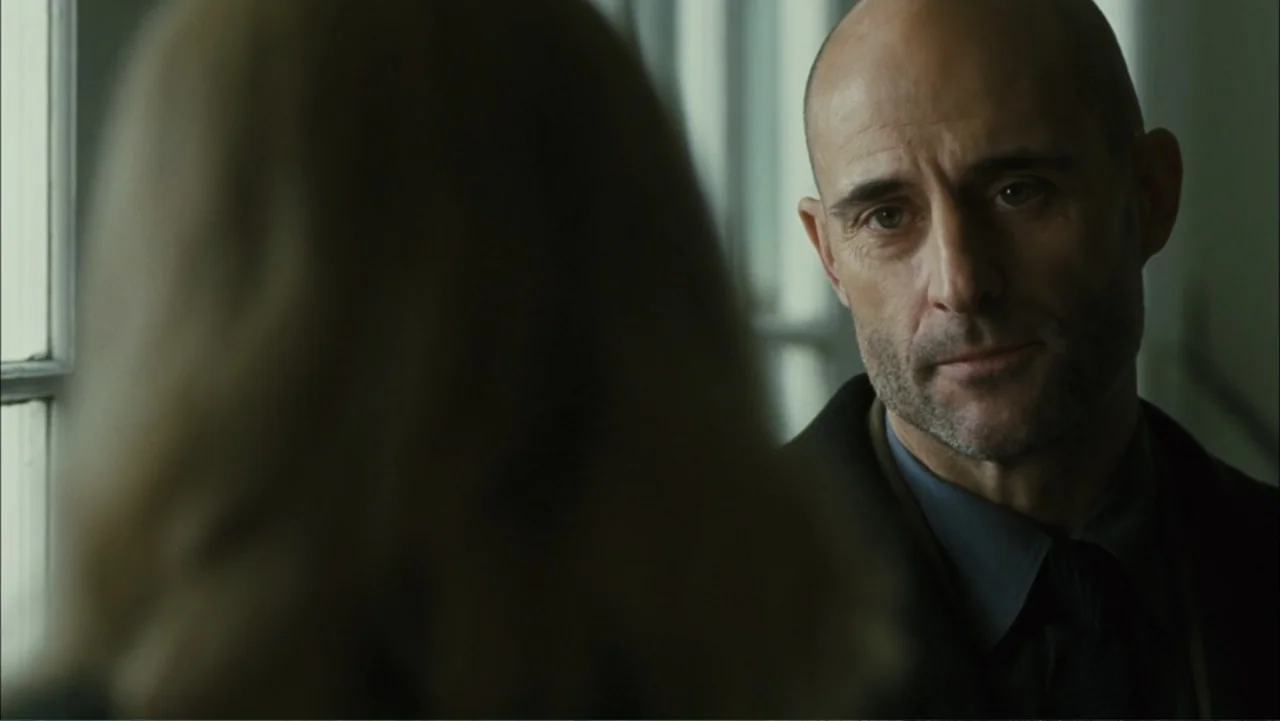 Before I Go to Sleep (2014) movie still: medium — A man stands indoors near a window with an out-of-focus person in the foreground. The man observes…