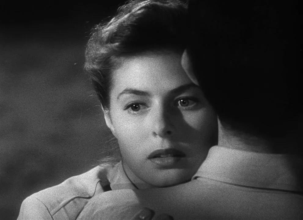 Spellbound (1945) movie still: closeup — A close-up shot focuses on a woman's face resting against a man's shoulder. The background is a dark,…