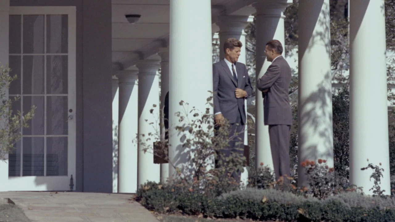 The Soul of America (2020) movie still: fullbody — A historic building exterior features a series of tall white columns and stone pavement. Two men…