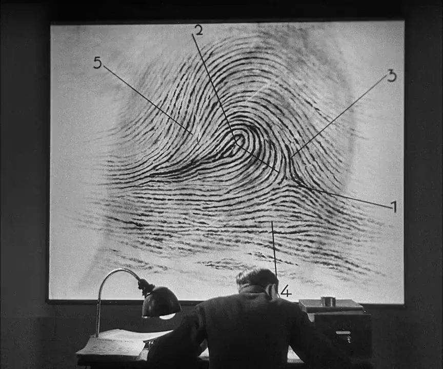 M (1931) movie still: medium — An office with a large projection screen displaying a numbered fingerprint diagram. A man sits at a desk with a lamp…