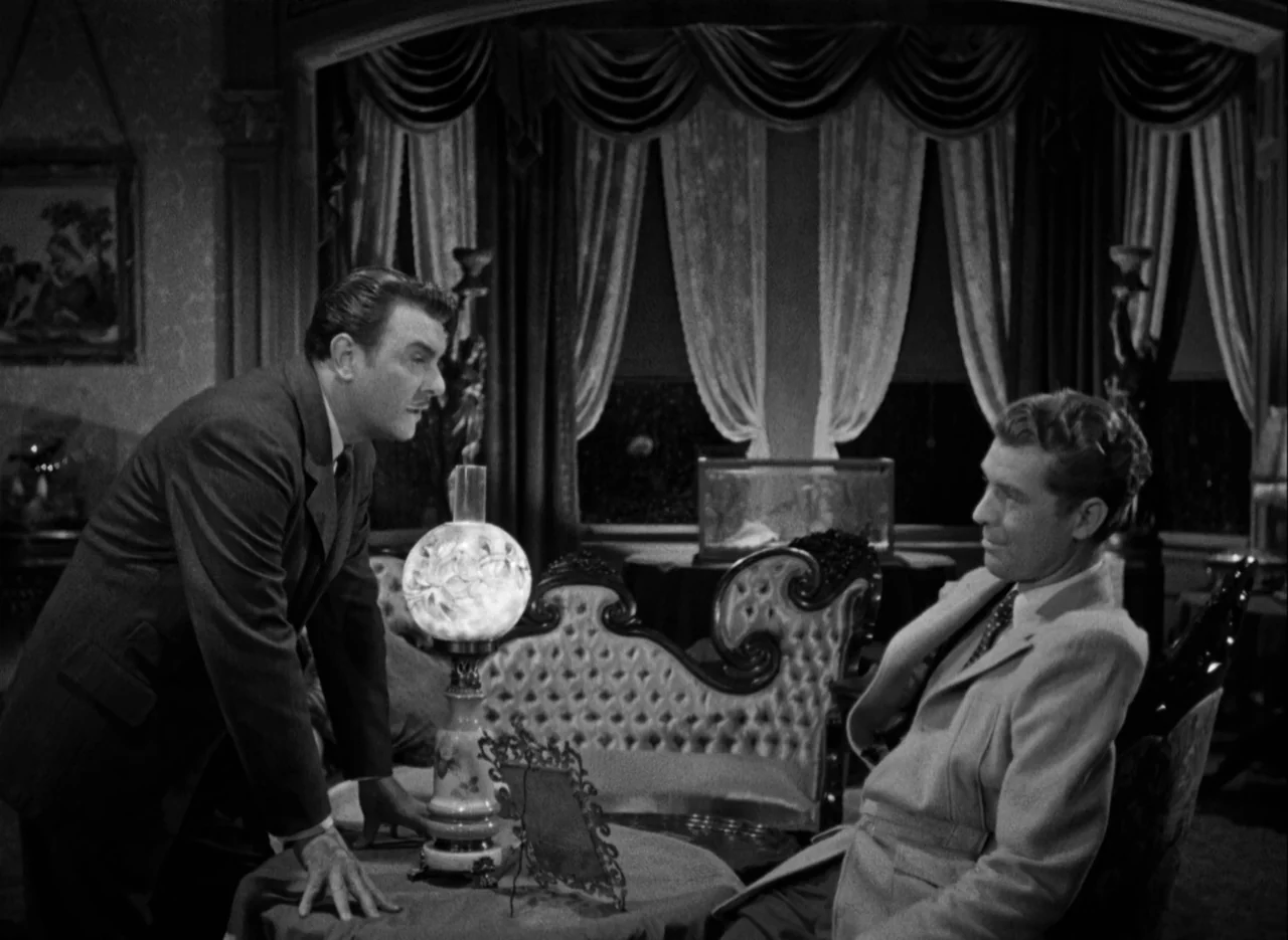 The Spiral Staircase (1946) movie still: medium — A dimly lit room features ornate Victorian furniture and heavy curtains draped over windows. Two…