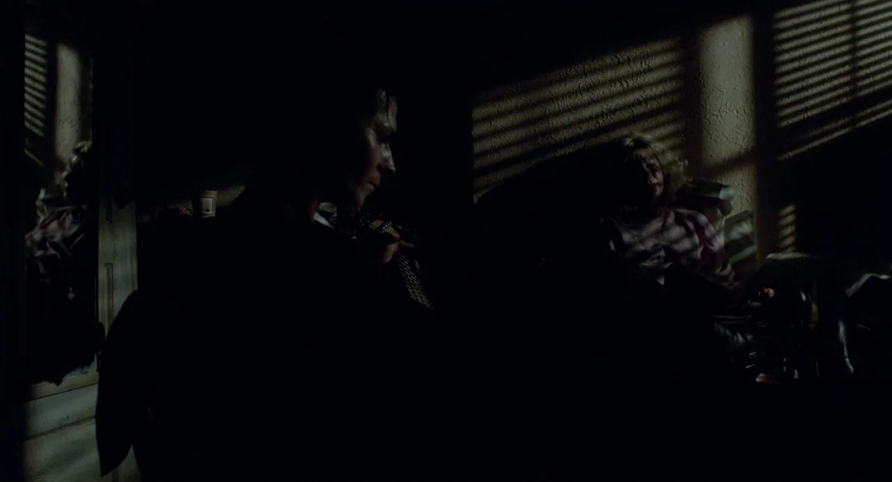 Sid and Nancy (1986) movie still: medium — A dimly lit room features walls textured with venetian blind shadow patterns. A man plays an acoustic…