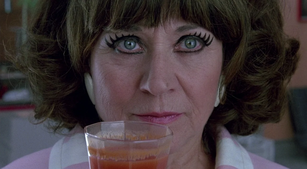 Women on the Verge of a Nervous Breakdown (1988) movie still: closeup — An interior space features a woman holding a glass of juice. She stares…