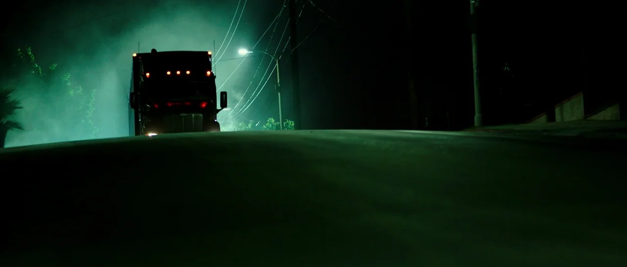 The Purge: Anarchy (2014) movie still: wide — A large semi-truck emerges over the horizon of an empty road at night. Thick green mist obscures the…