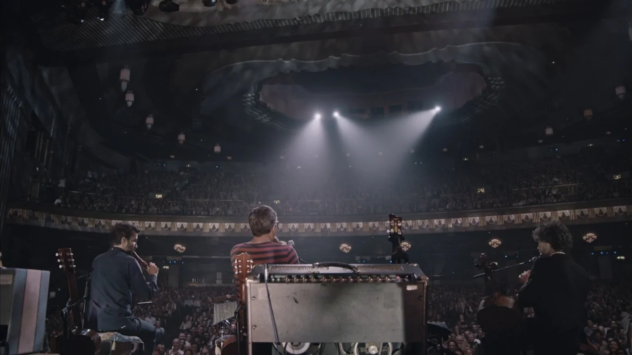 Flight of the Conchords: Live in London (2018) movie still: wide — A large multi-tiered concert hall is filled with a seated audience in darkness.…