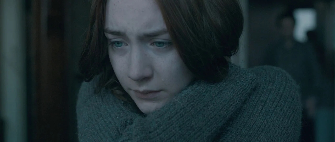 Byzantium (2012) movie still: closeup — A dimly lit interior space with muted colors. A young woman looks downward with a tear on her cheek while…