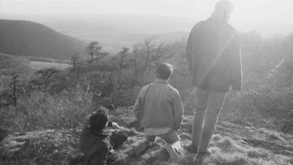 Who’s That Knocking At My Door (1967) movie still: wide — Three individuals stand on a grass-covered ridge overlooking a vast, hilly landscape. The…