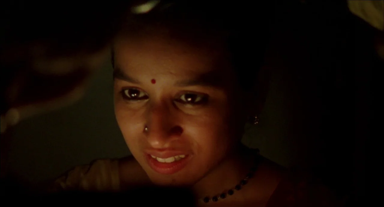 Monsoon Wedding (2001) movie still: closeup — A dimly lit room with a subject centered in a low-key lighting environment. A woman with a bindi looks…