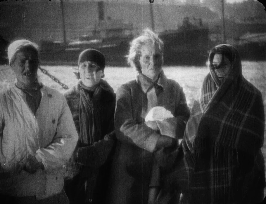 Battleship Potemkin (1925) movie still: medium — A group of four women stand on a harbor pier near a large ship. They face the camera with static…