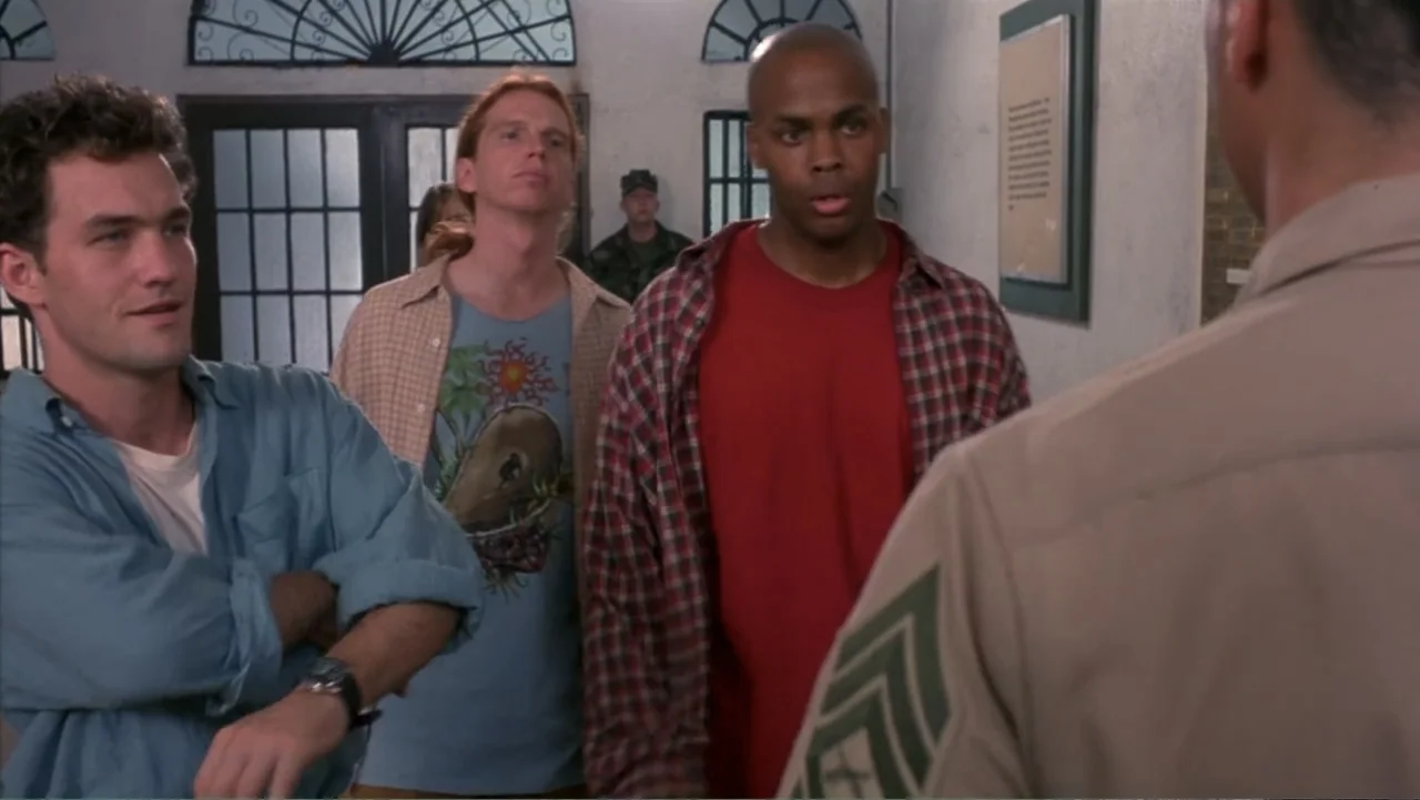 Behind Enemy Lines (2001) movie still: medium — A military building hallway with white walls and arched doorways showing a soldier. Three young men…