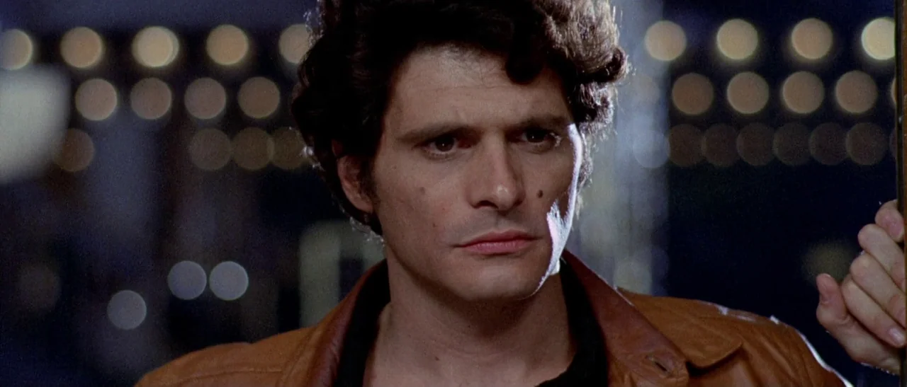 The Bird With The Crystal Plumage (1970) movie still: closeup — An urban setting at night with out-of-focus city lights in the background. A young…