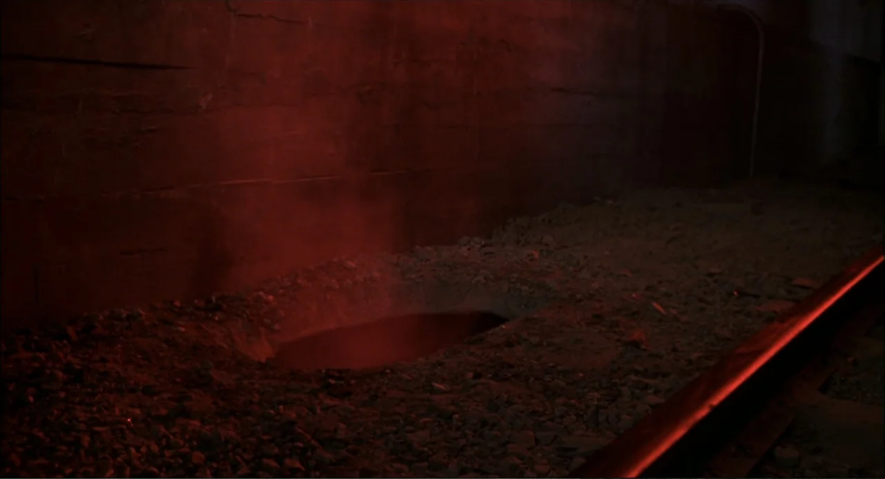 Little Nicky (2000) movie still: wide — A dark subterranean corridor features a dirt floor with a small steaming circular hole. The rough concrete…