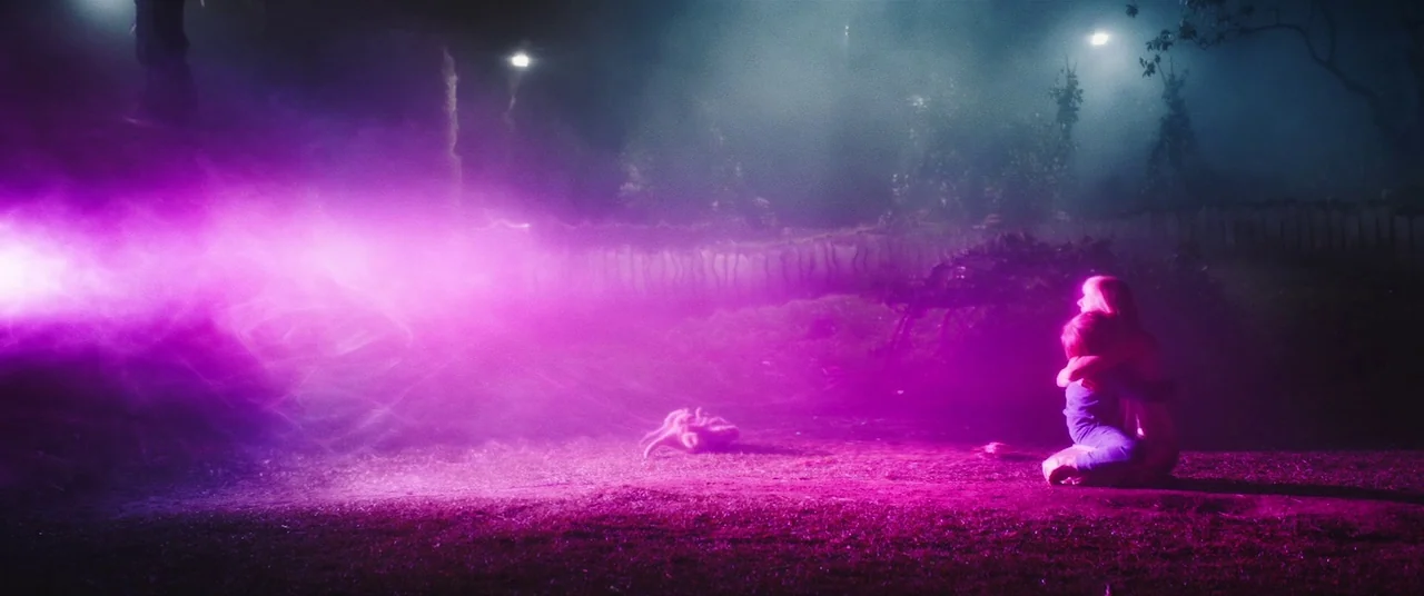 Colour Out of Space (2020) movie still: wide — A night park scene features a dark grassy area with distant trees and foliage. Two people embrace…