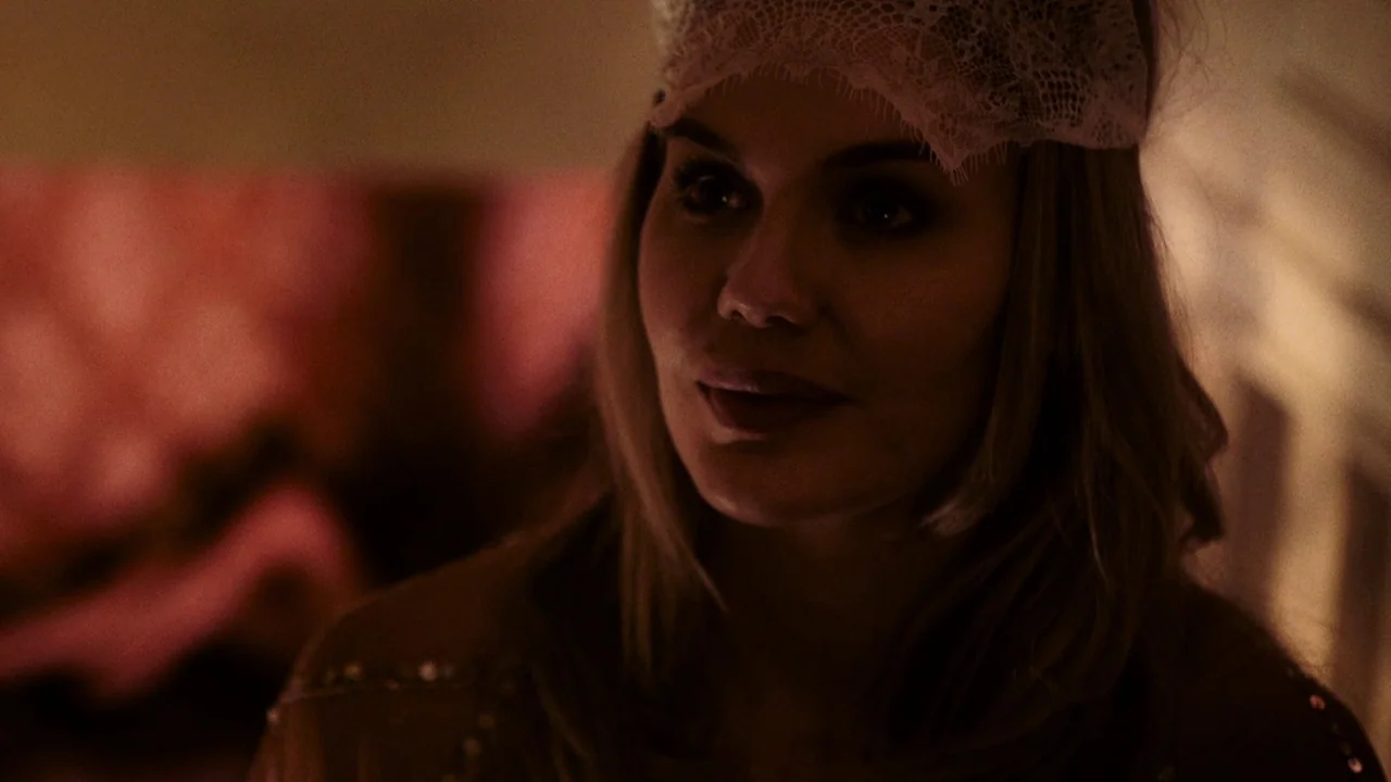 Snowbound (2017) movie still: closeup — A dimly lit indoor space with soft, warm illumination against a dark background. A woman wearing a lace…