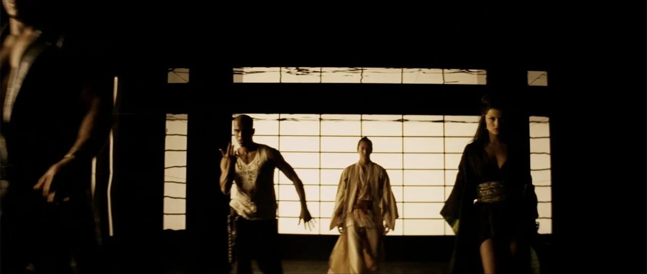 Elektra (2005) movie still: fullbody — A dark interior with backlit translucent shoji paper screens covering the wall. Three people walk toward the…