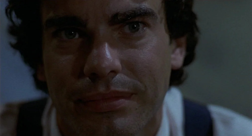 Sex, Lies And Videotape movie still: closeup — A man stands in a dimly lit room with dark, indistinct surroundings. The subject faces the camera…