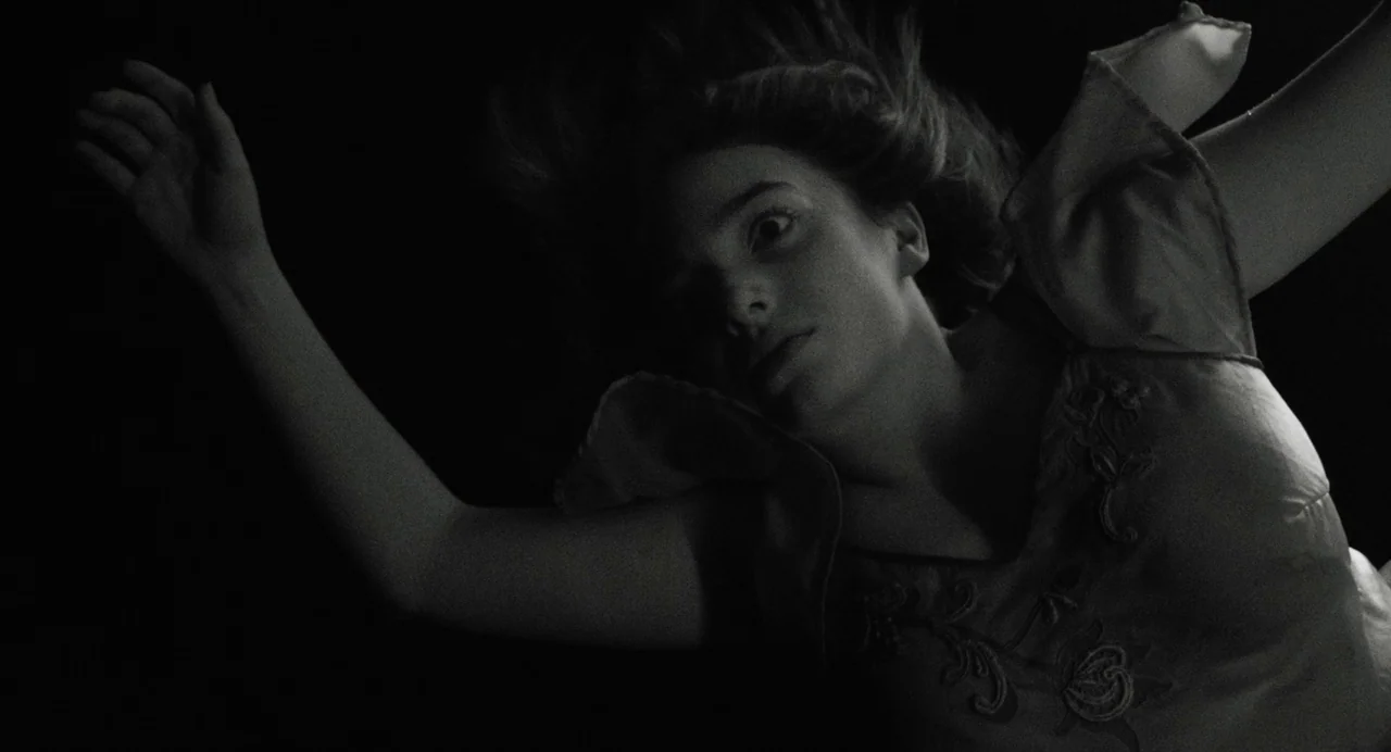 A Haunting In Venice (2023) movie still: medium — A woman drifts through a dark, undifferentiated void with hair floating around her head. Her…