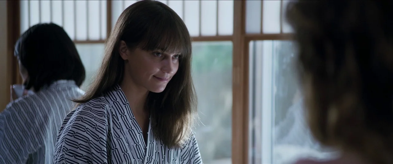 Earthquake Bird movie still: medium — A Japanese-style interior with shoji screen windows and natural light. A woman in a patterned robe faces the…