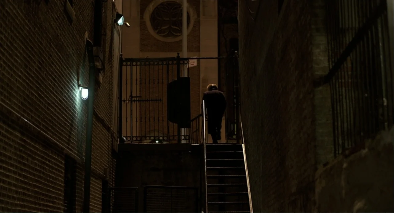 Norman: The Moderate Rise and Tragic Fall of a New York Fixer (2016) movie still: wide — A narrow urban alleyway with brick walls and a metal…