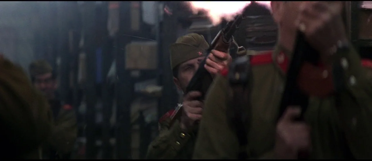 GoldenEye (1995) movie still: medium — A dark, cluttered interior space with multiple soldiers in military uniforms. One man holds a rifle to his…
