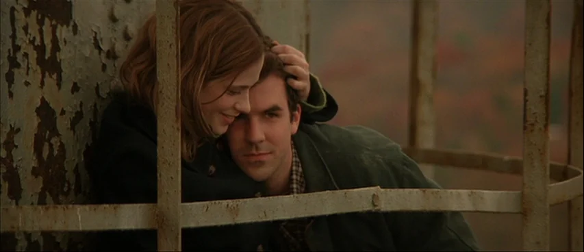 All The Real Girls (2003) movie still: medium — A couple leans against a weathered metal structure on a high observation platform. The blurred…