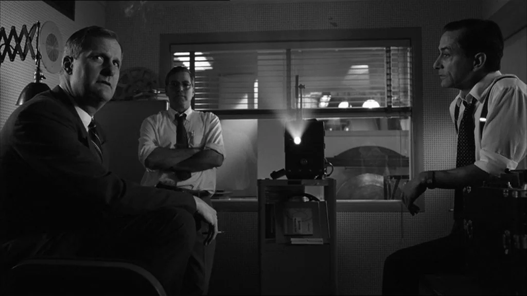 Good Night And Good Luck (2005) movie still: medium — A dark projection room with perforated walls and a small window behind the projector. Three…