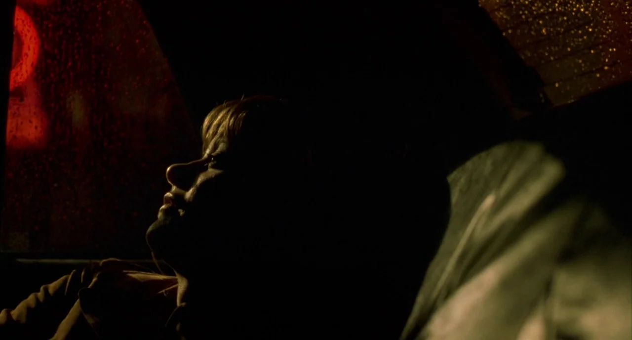 In The Cut (2003) movie still: closeup — The interior of a moving car at night is dark and dimly lit. A young woman rests her head against the…