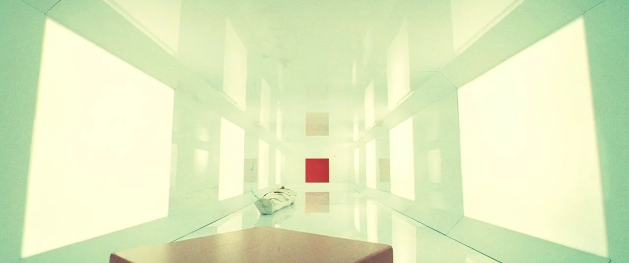 Beyond The Black Rainbow (2010) movie still: wide — A long symmetrical white corridor features walls illuminated by large recessed light panels. A…