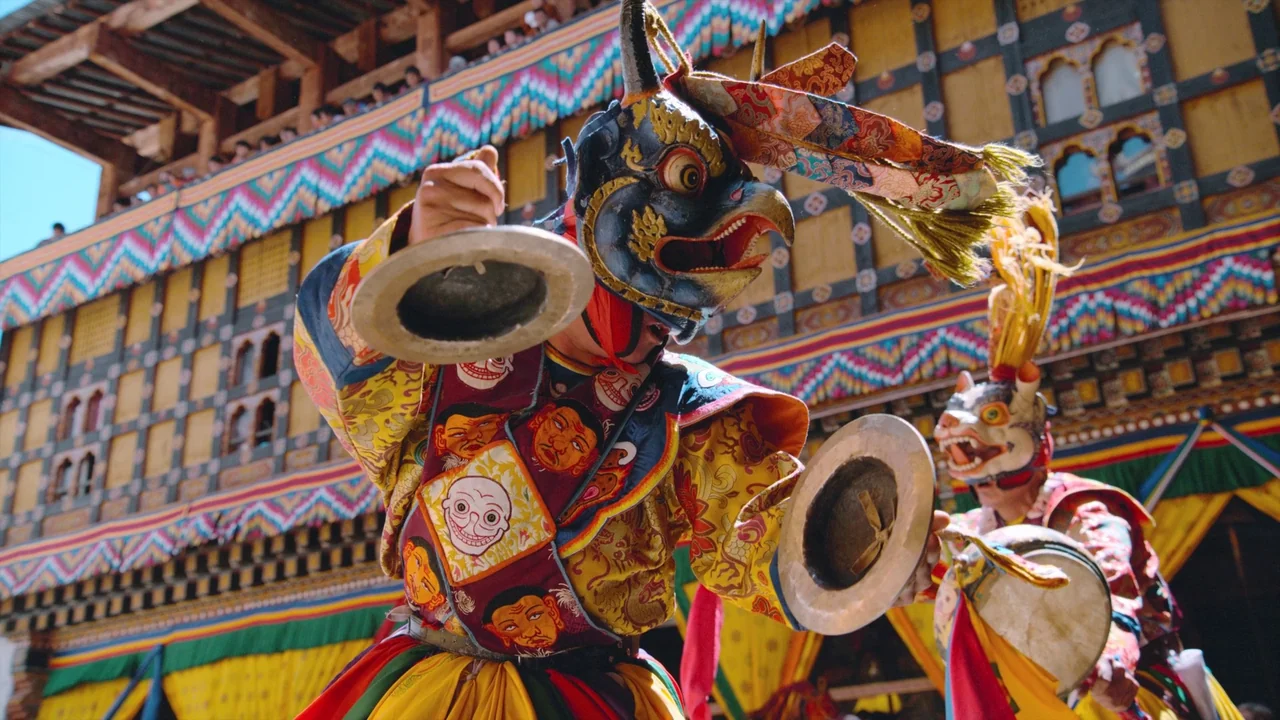 Awaken (2018) movie still: A vibrant, high-energy capture of a traditional Bhutanese monastic mask dance. The performers, adorned in intricate,…