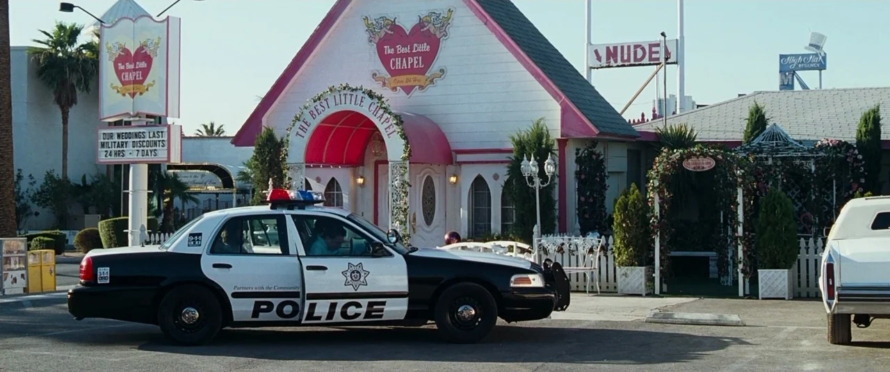 The Hangover (2009) movie still: wide — A roadside wedding chapel features a white facade with pink trim and heart signage. A police cruiser is…