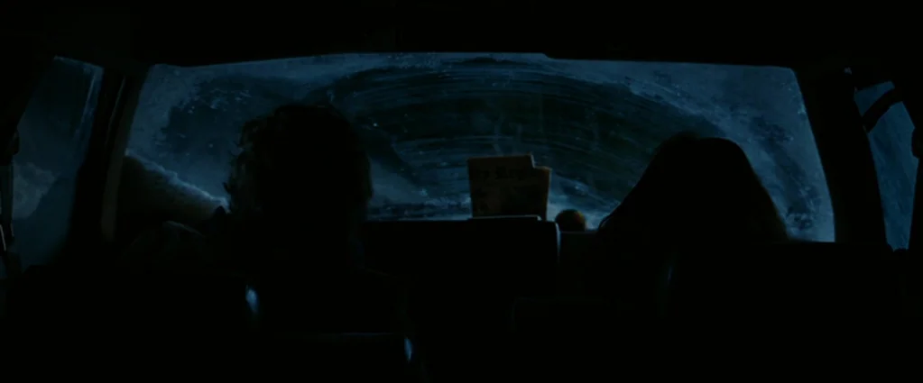 Wind Chill (2007) movie still: medium — Two people are silhouetted inside a vehicle at night with a frosty, obscured windshield. A newspaper sits on…