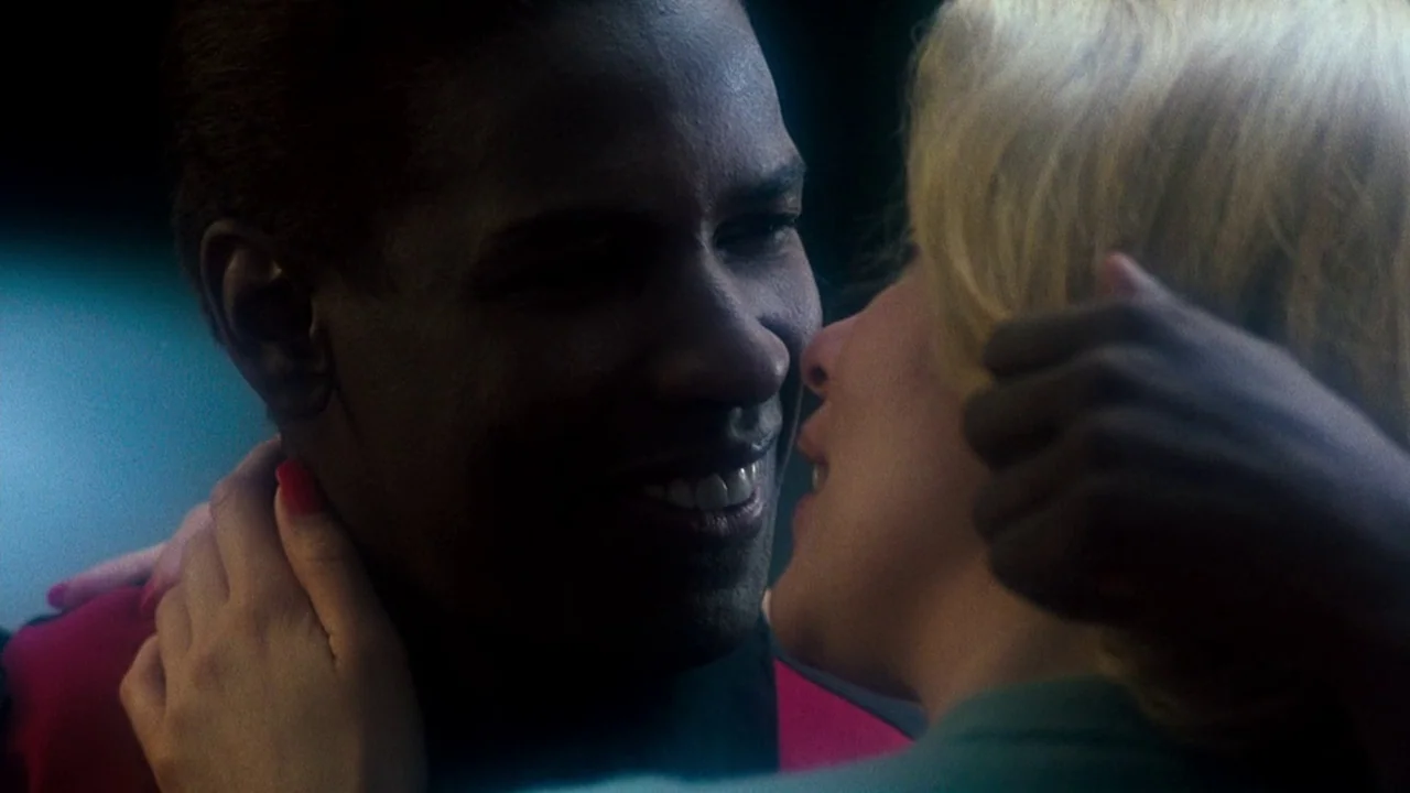 Malcolm X (1992) movie still: closeup — A dark, dimly lit environment where two people are dancing in close proximity. The man smiles while the…