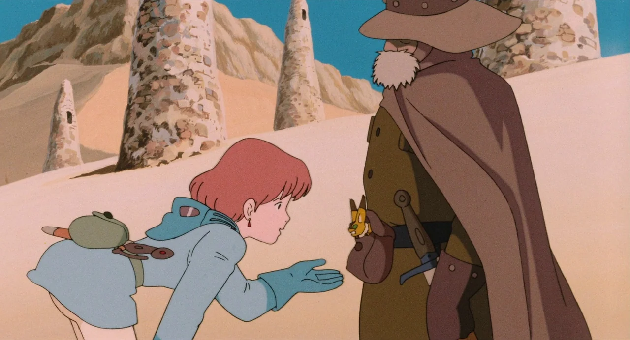 Nausicaä of the Valley of the Wind (1984) movie still: medium — An arid, sandy desert landscape features several tall, weathered stone towers in the…