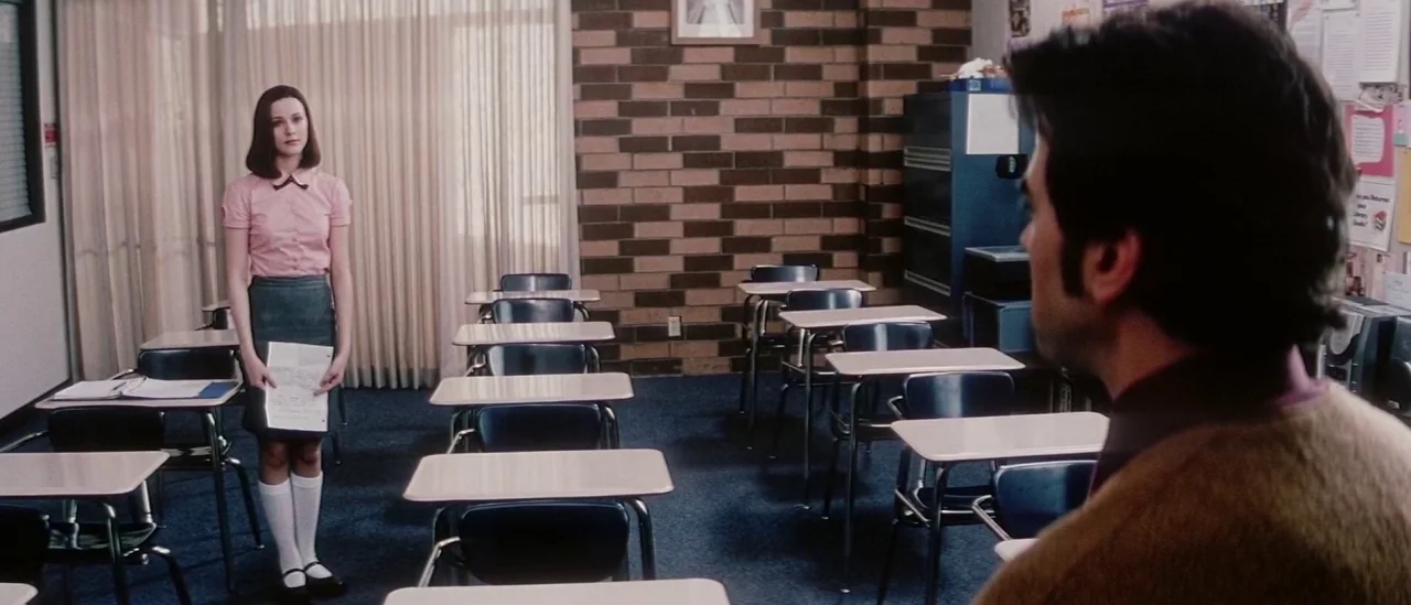 Pretty Persuasion (2005) movie still: medium — A quiet room with rows of student desks facing a brick wall and window. A young woman in a uniform…