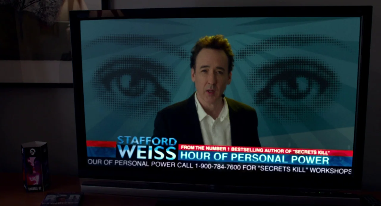 Maps to the Stars (2014) movie still: medium — A television screen displays a broadcast featuring a man presenting a self-help program. The screen…