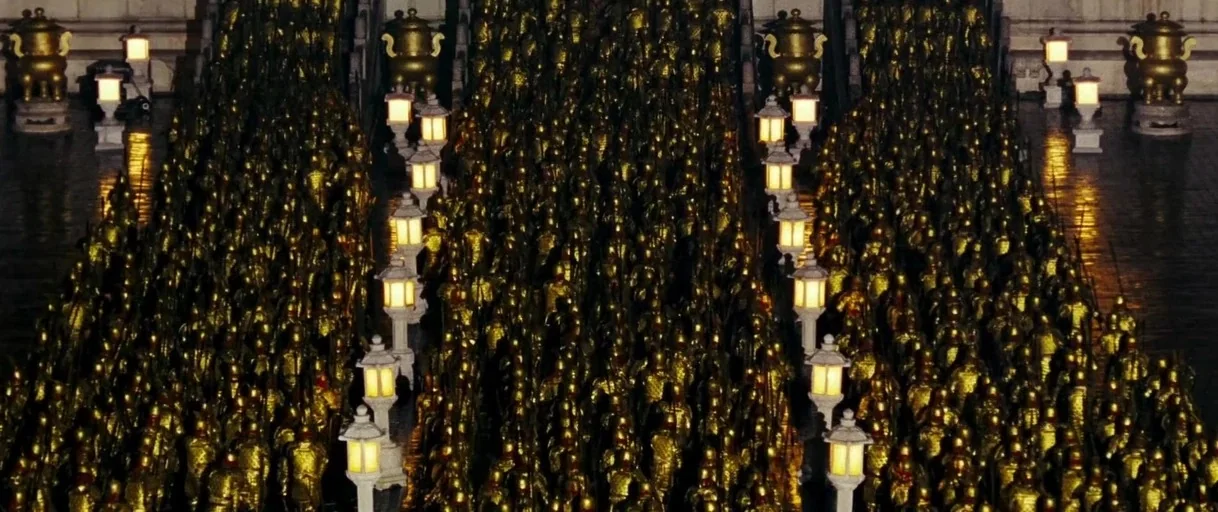 Curse of the Golden Flower (2006) movie still: wide — A massive crowd of soldiers in ornate gold armor fills a stone courtyard at night. Tall white…