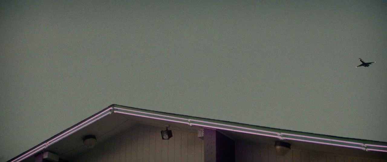 Triple 9 (2016) movie still: wide — A low-angle view of a flat-roofed building with modern architectural lines against a sky. A small silhouette of…