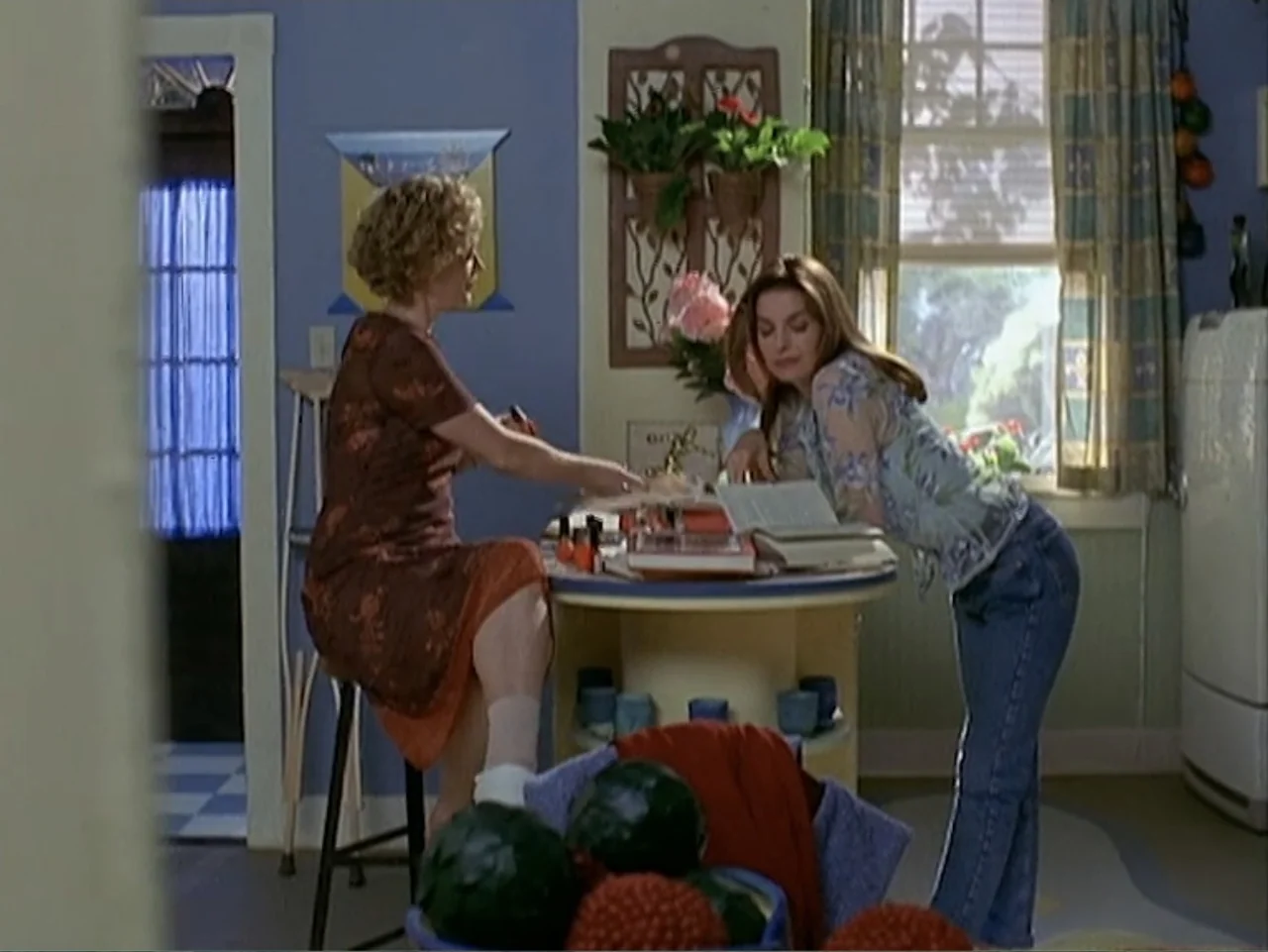 Catch a Falling Star (2000) movie still: medium — A 1990s kitchen features light blue walls, a round table, and a window. One woman sits on a stool…