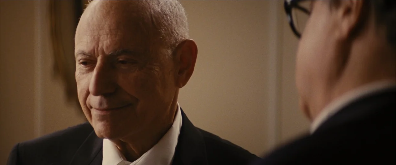 Argo (2012) movie still: medium — A well-lit interior office space with a blurred light wall in the background. An older man with short gray hair in…