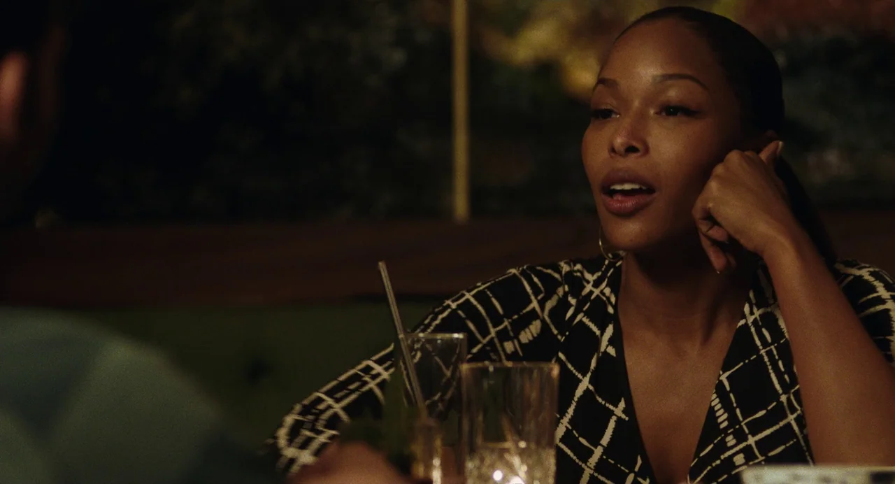 Test Pattern (2019) movie still: medium — A dark restaurant booth serves as the setting for a conversation at night. A woman in a patterned blouse…