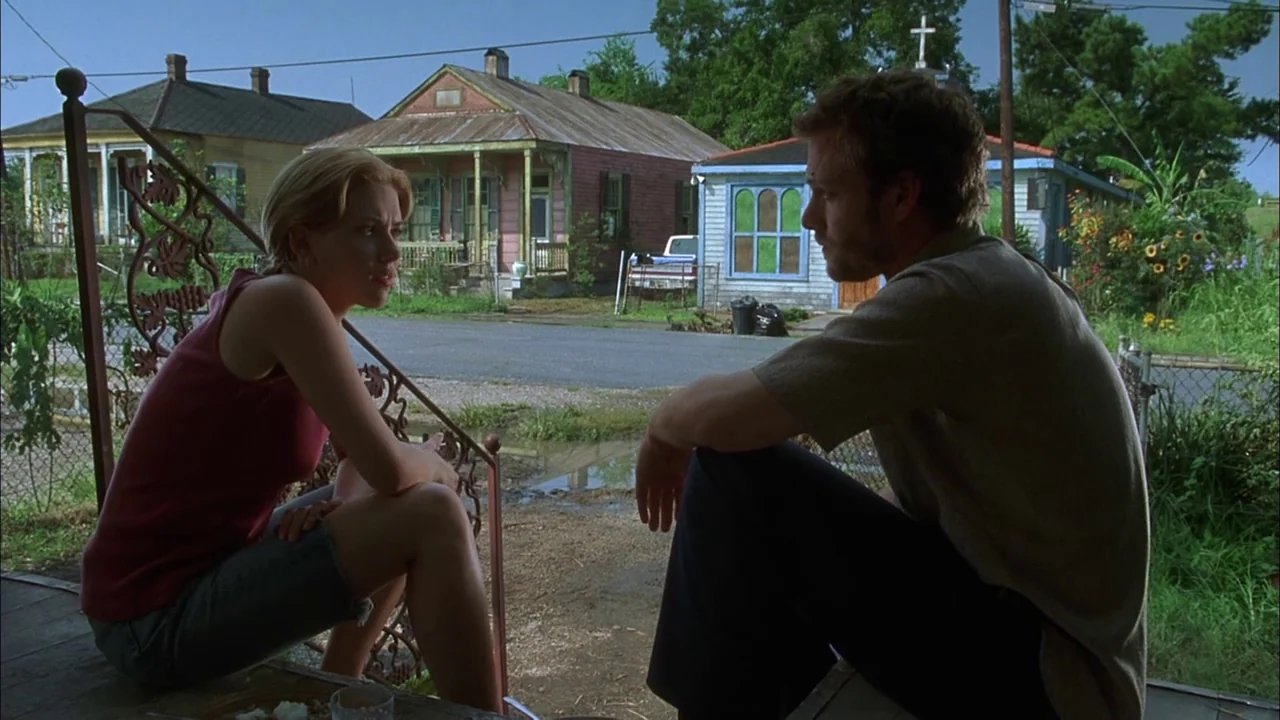 Love Song For Bobby Long (2004) movie still: fullbody — A residential street in a rural town features colorful wooden houses with porches. A blonde…