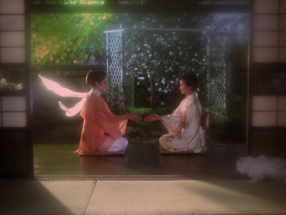 House (Hausu) (1977) movie still: wide — Two women kneel facing each other in a room with traditional shoji screens. They extend their hands toward…