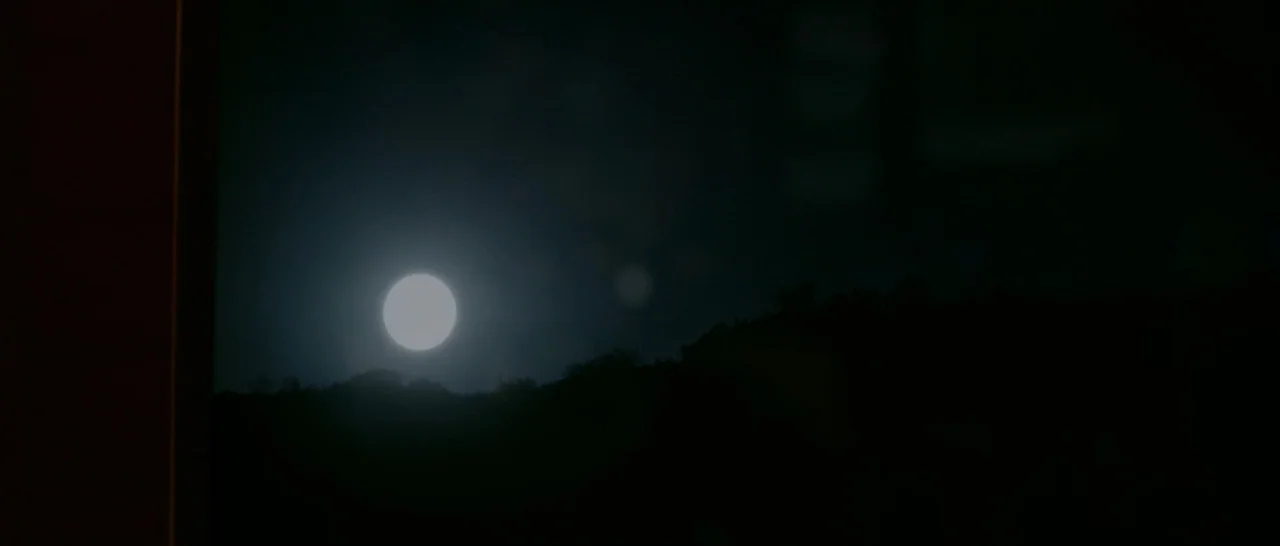 The Invitation (2015) movie still: establishing — A bright full moon illuminates the dark, silhouetted crest of a distant ridge. The sky remains…