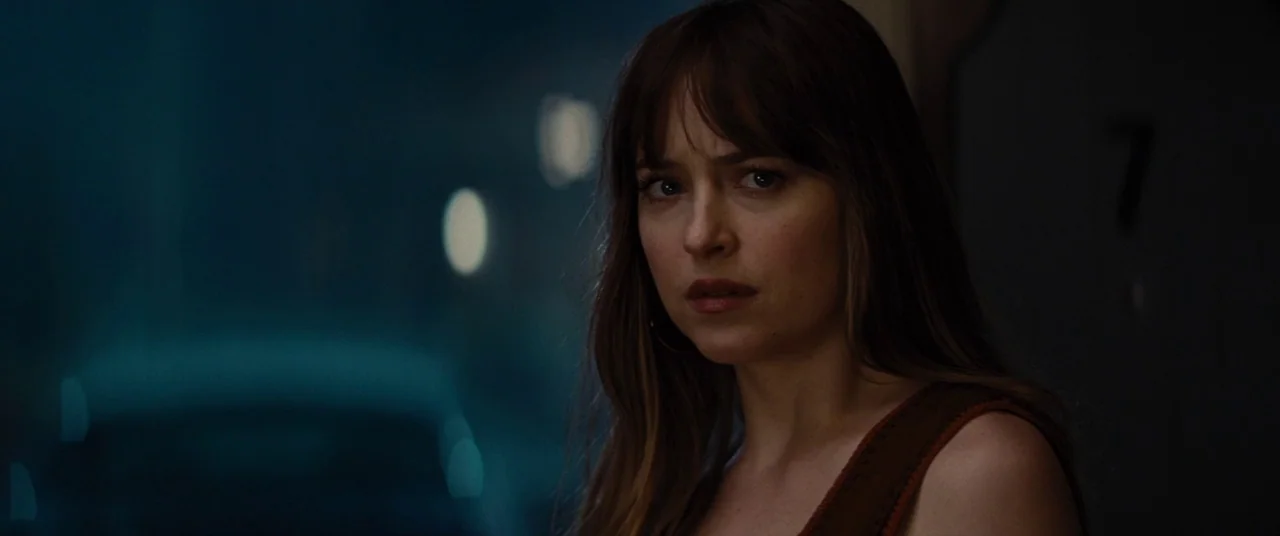 Bad Times at the El Royale (2018) movie still: closeup — A woman stands in the dim light outside of a motel door at night. The background features…