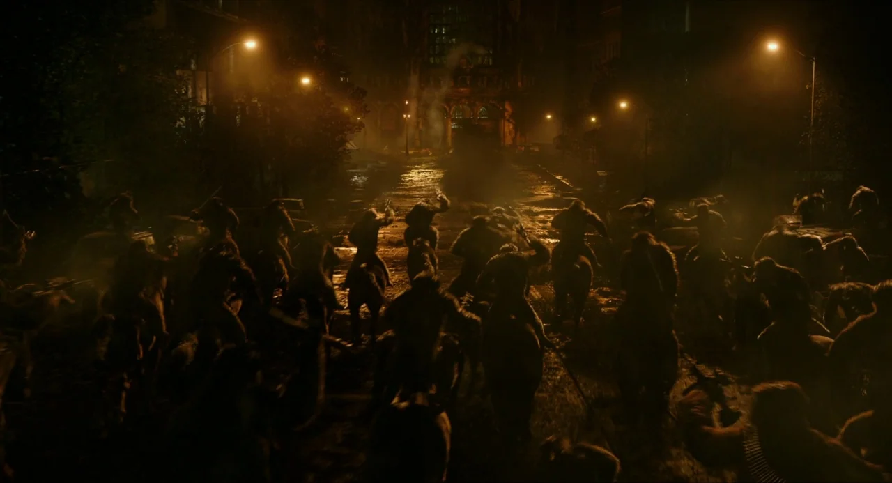 Dawn of the Planet of the Apes (2014) movie still: wide — A large mass of apes riding horses charges down a dark, rain-slicked city road.…