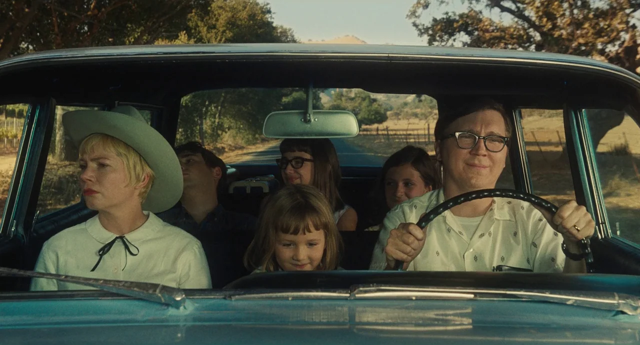 The Fabelmans (2022) movie still: medium — A vintage car cabin with a group of six family members seated inside. They are traveling along a rural…