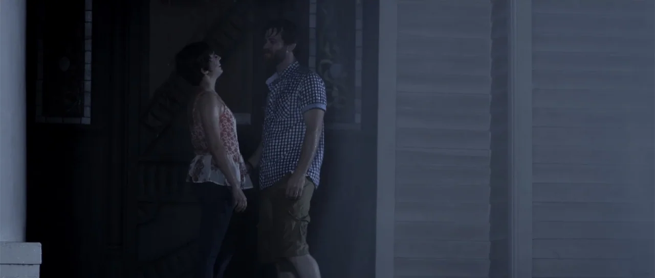 Night People (1954) movie still: medium — A residential house exterior porch during the night with faint ambient blue light. A man and a woman stand…