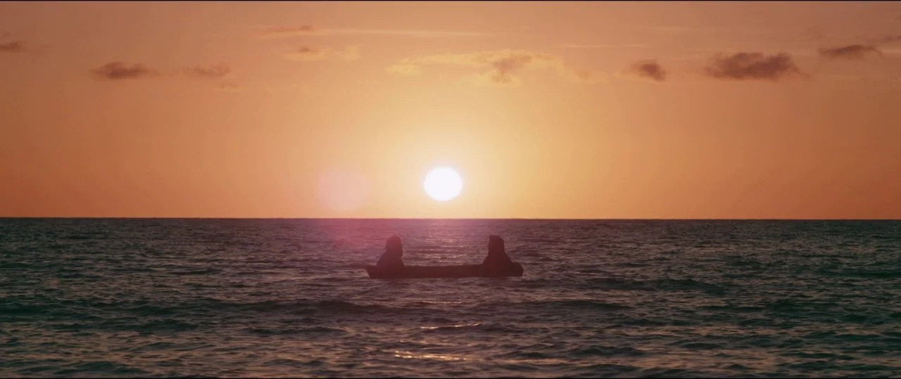 Buster’s Mal Heart (2016) movie still: wide — Two figures are centered in a small boat on the open ocean surface. The horizon line is perfectly…