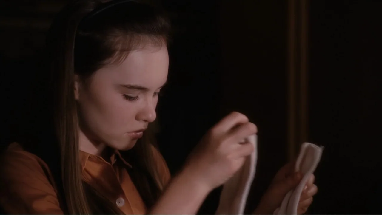 Flipped (2010) movie still: closeup — A dark indoor space provides the setting for a portrait of a young girl. The girl stands against a dark…