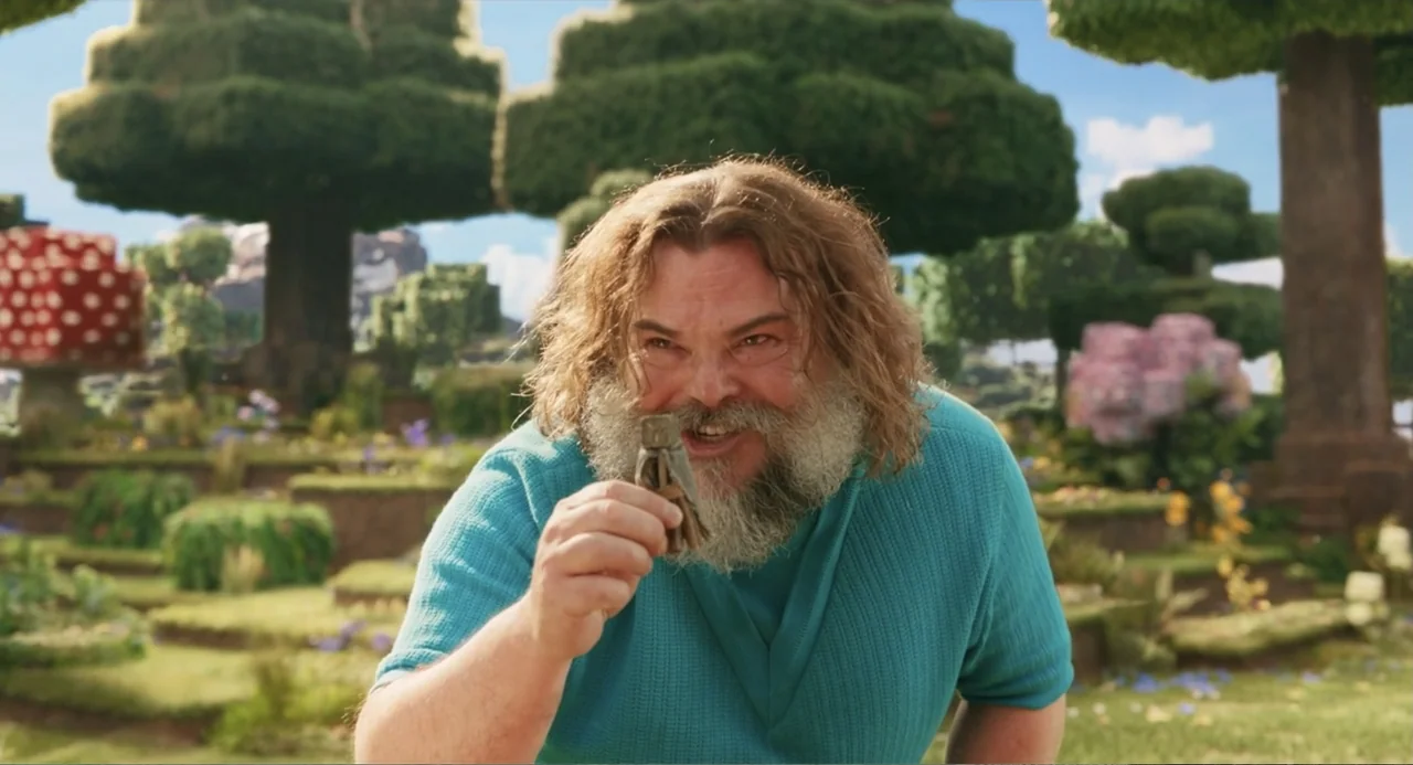 A Minecraft Movie (2025) movie still: medium — An outdoor landscape features blocky stylized trees and tiered grassy platforms. A man holds a small…